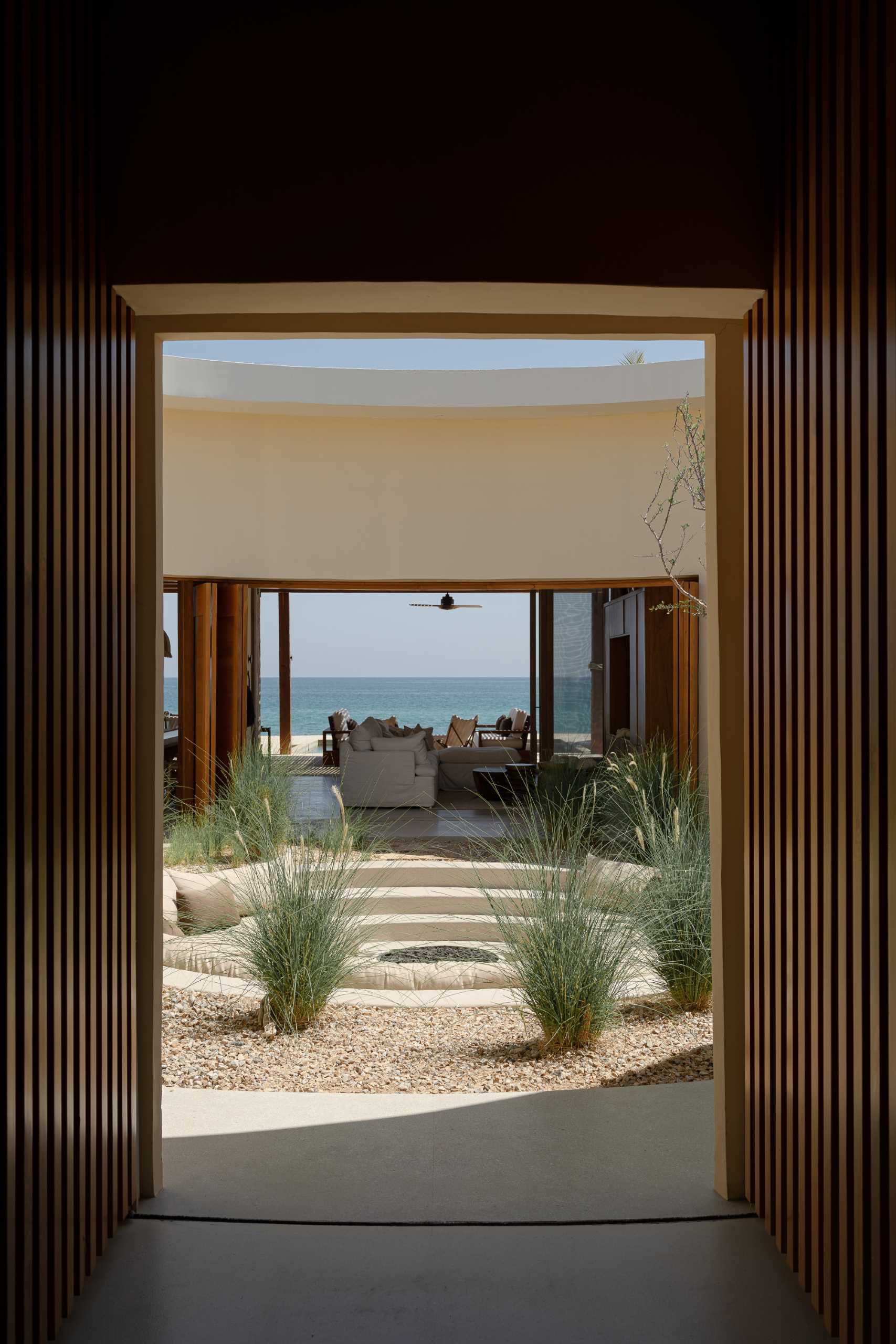 A contemporary house has an internal courtyard, at the center of this circular space lies a fire pit, surrounded by a sunken circular sofa that invites gathering and contemplation.