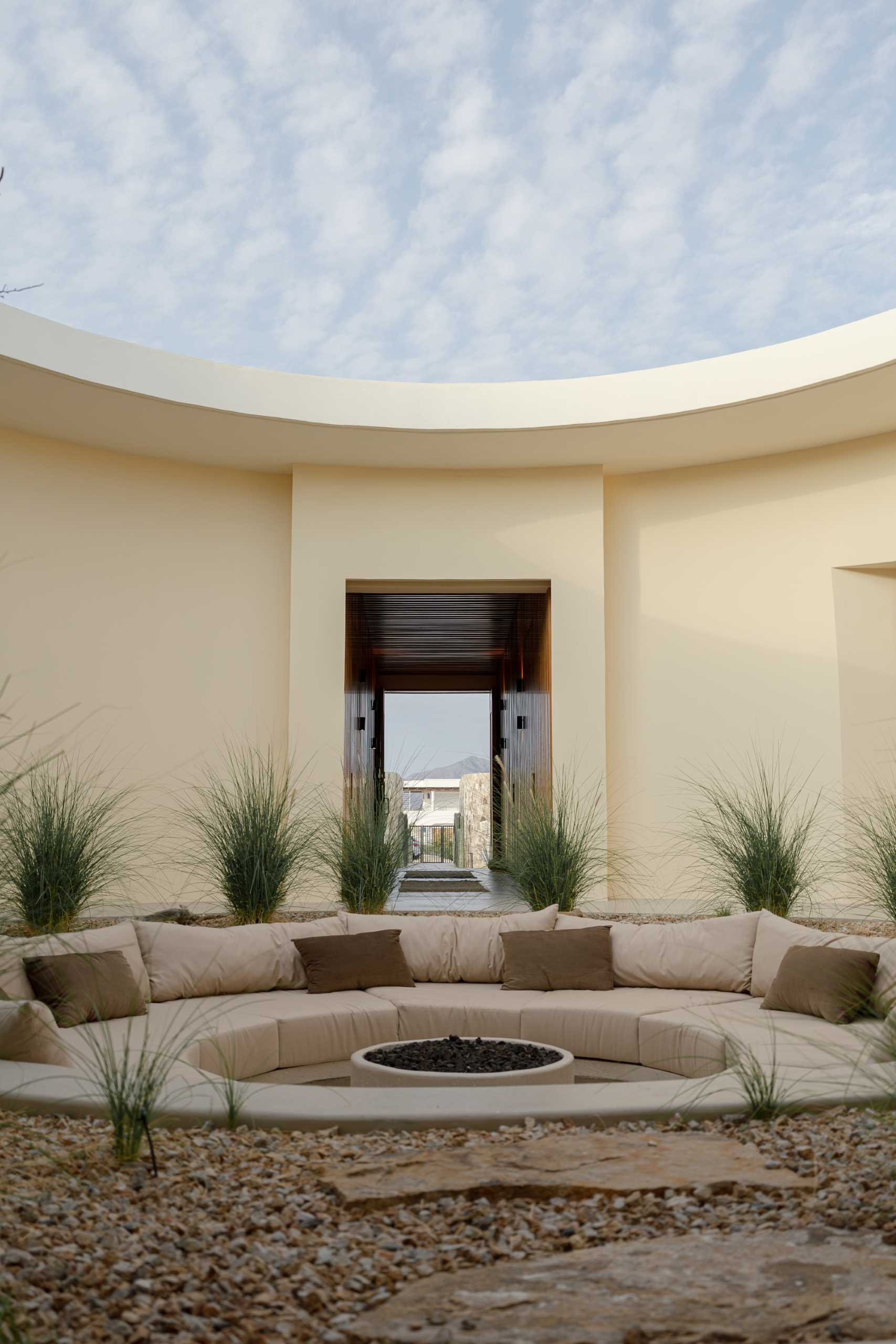A contemporary house has an internal courtyard, at the center of this circular space lies a fire pit, surrounded by a sunken circular sofa that invites gathering and contemplation.