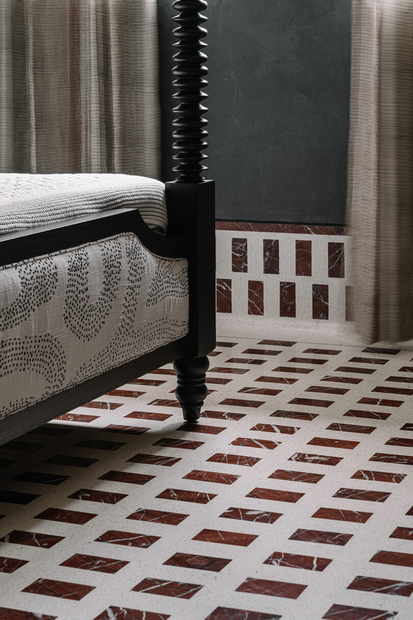 A stylish bedroom corner by Studio Nishita Kamdar features a dark wood bed and a patterned floor of alternating brown and white rectangles.