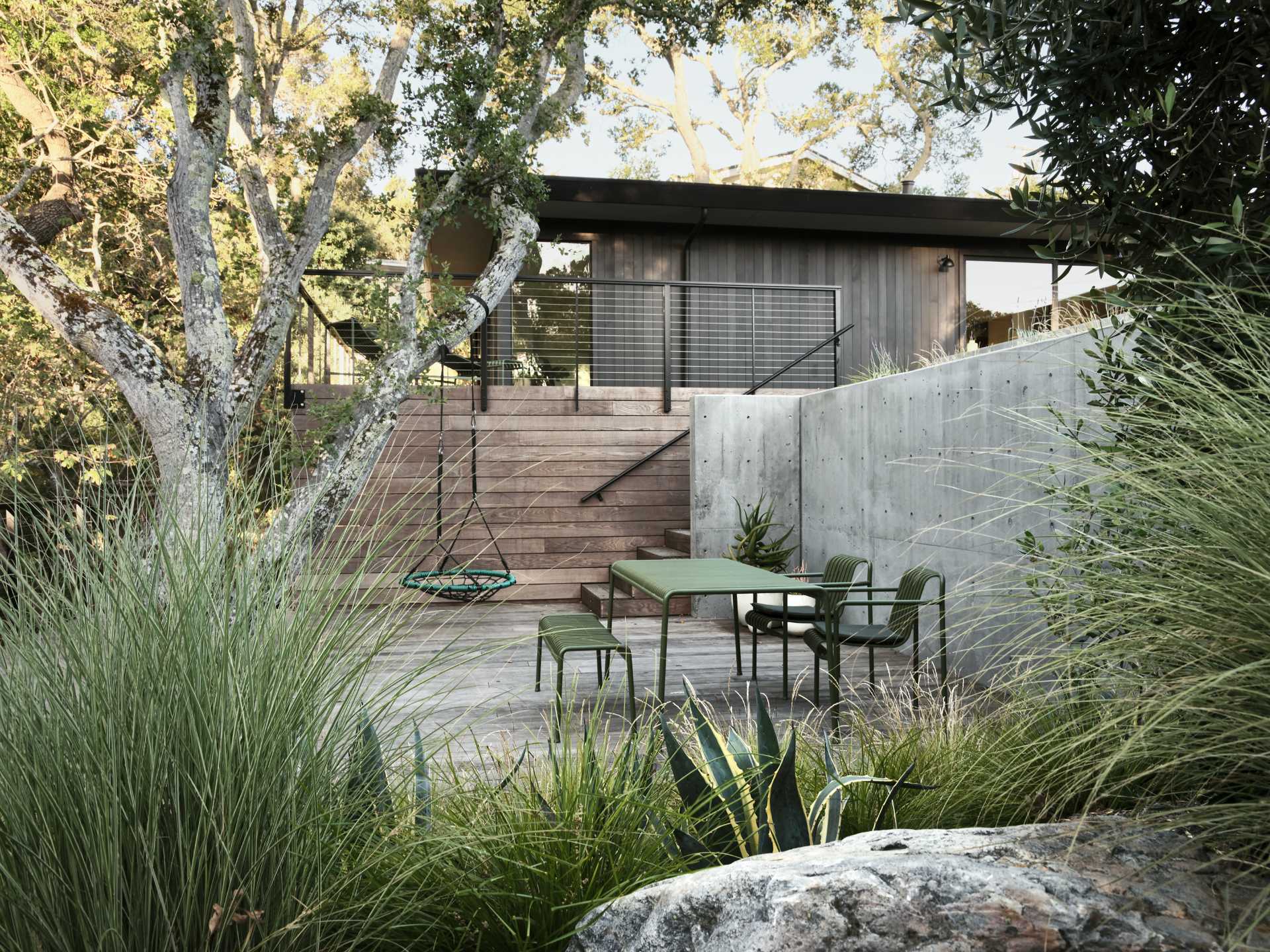 In the rear yard, an old patio and plain backyard was replaced with concrete walls that create two distinct, layered outdoor living spaces, emphasizing the new modern aesthetic and adding structure to the experience of the site and architecture.