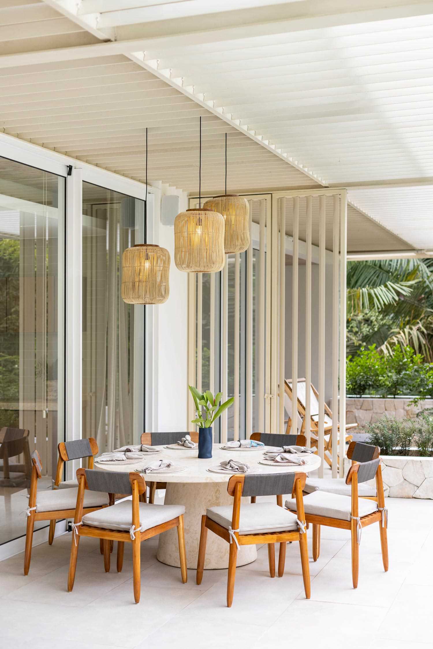 This intimate outdoor dining area features a round table surrounded by stylish wood chairs, creating the perfect blend of rustic warmth and modern comfort. Ambient lighting and nearby lush plants add to the inviting atmosphere.