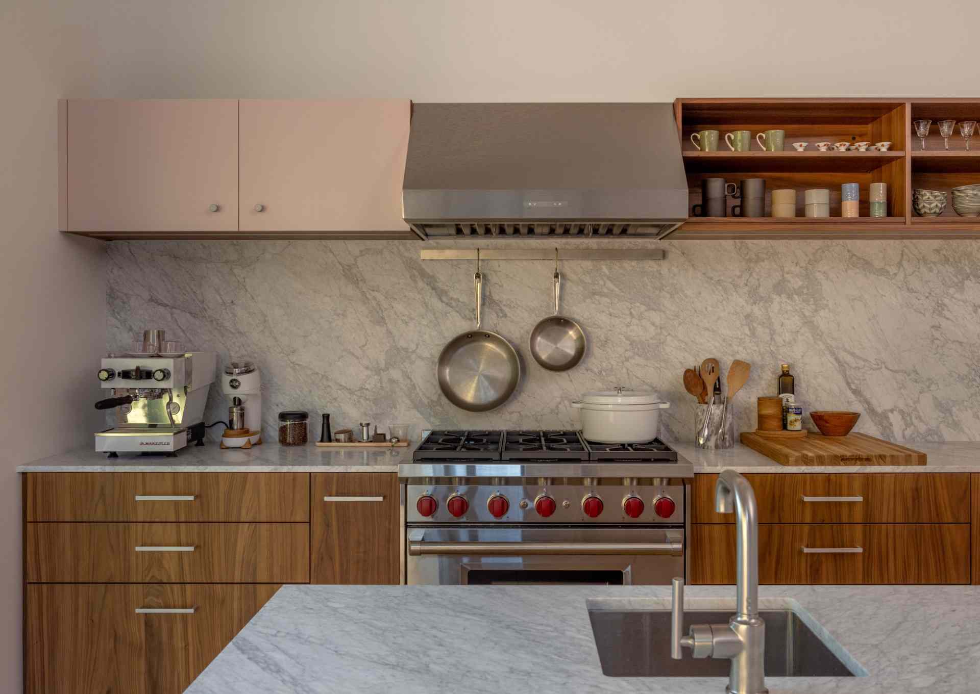 This modern kitchen opens to a small backyard with a concrete sitting wall, firepit, and outdoor cooking areas.