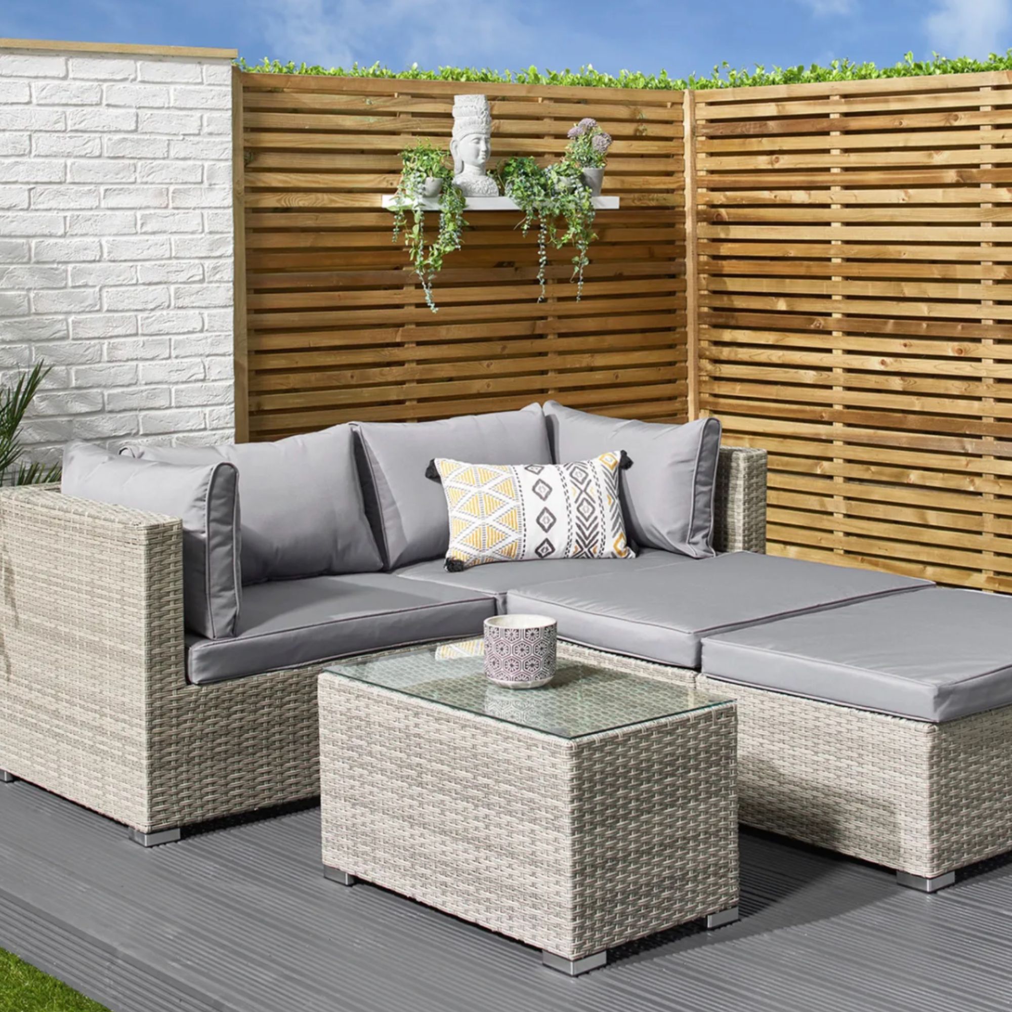 A grey rattan outdoor corner sofa with matching coffee table