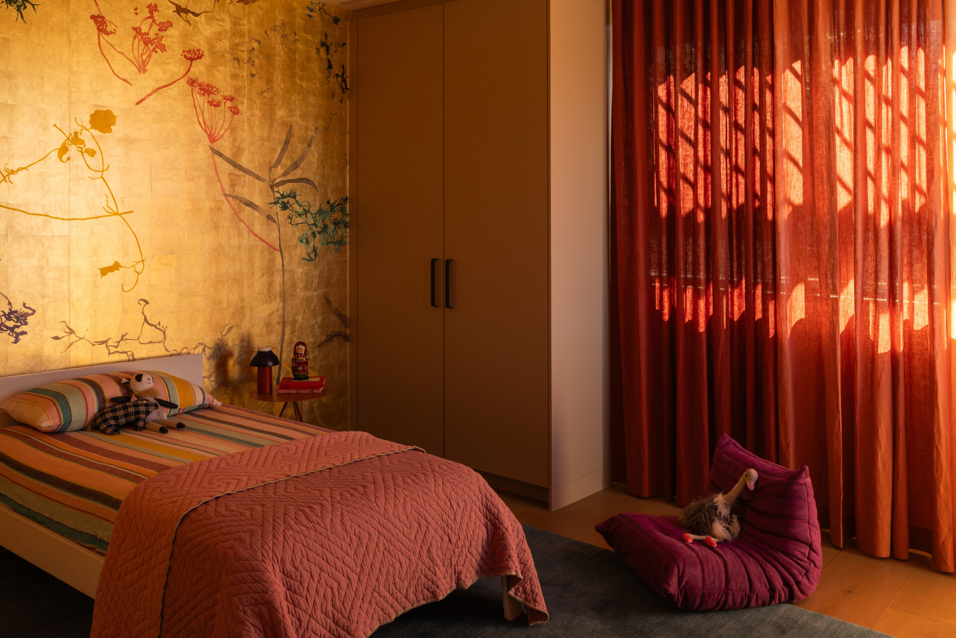 The kids’ bedroom strikes a balance between fun and finesse. A Calico wallcovering and Armadillo rug create a cozy, visually rich space that respects both play and rest.