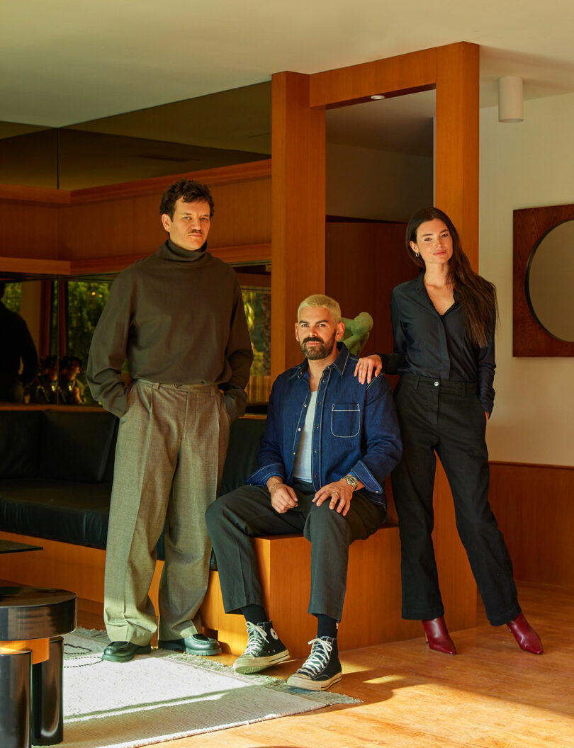 Three people pose for a photo inside a contemporary living space.