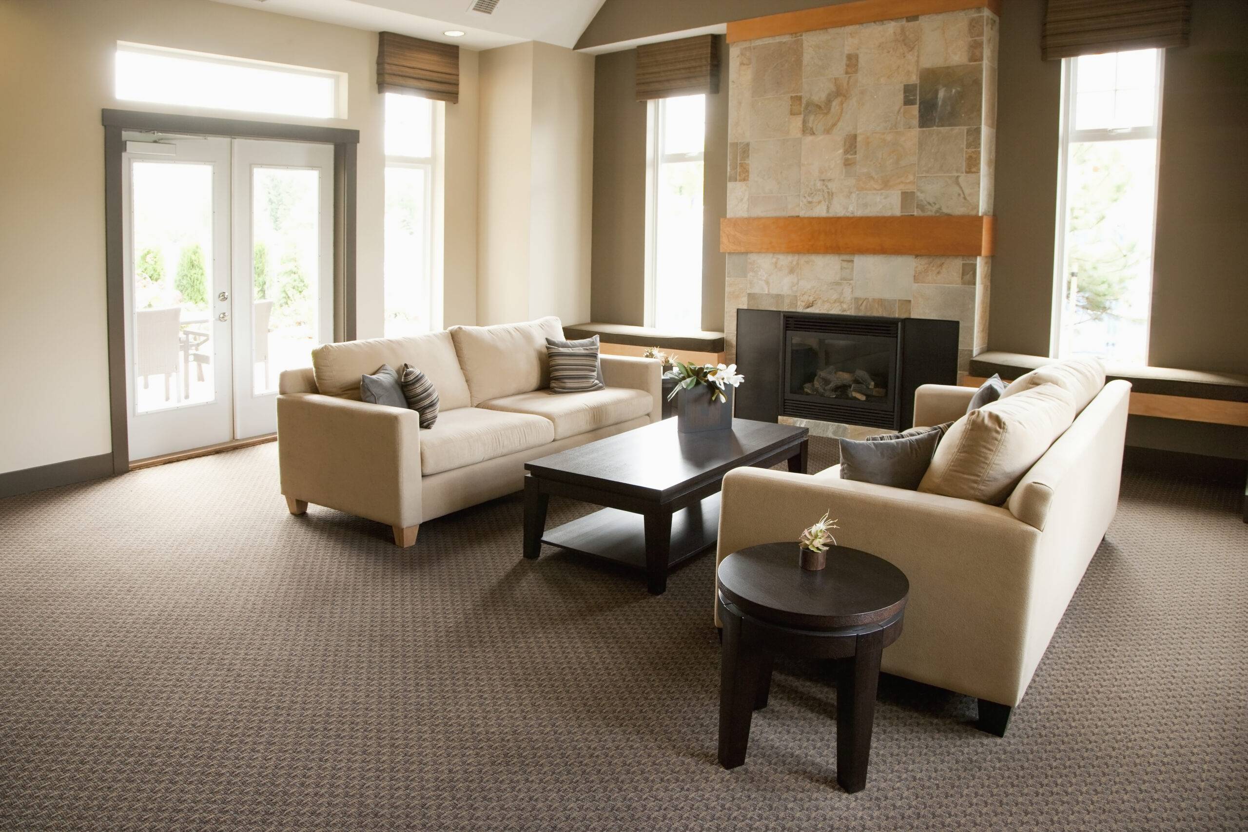An open living room with large windows and a carpeted floor.
