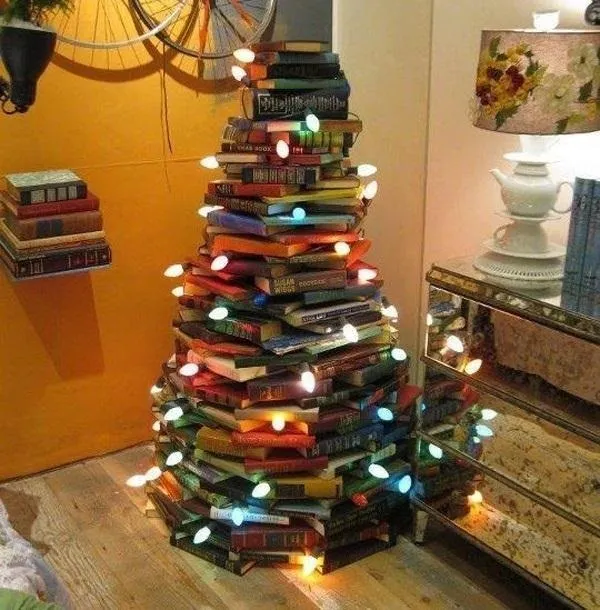 A decorative holiday tree made of stacked books with lights.