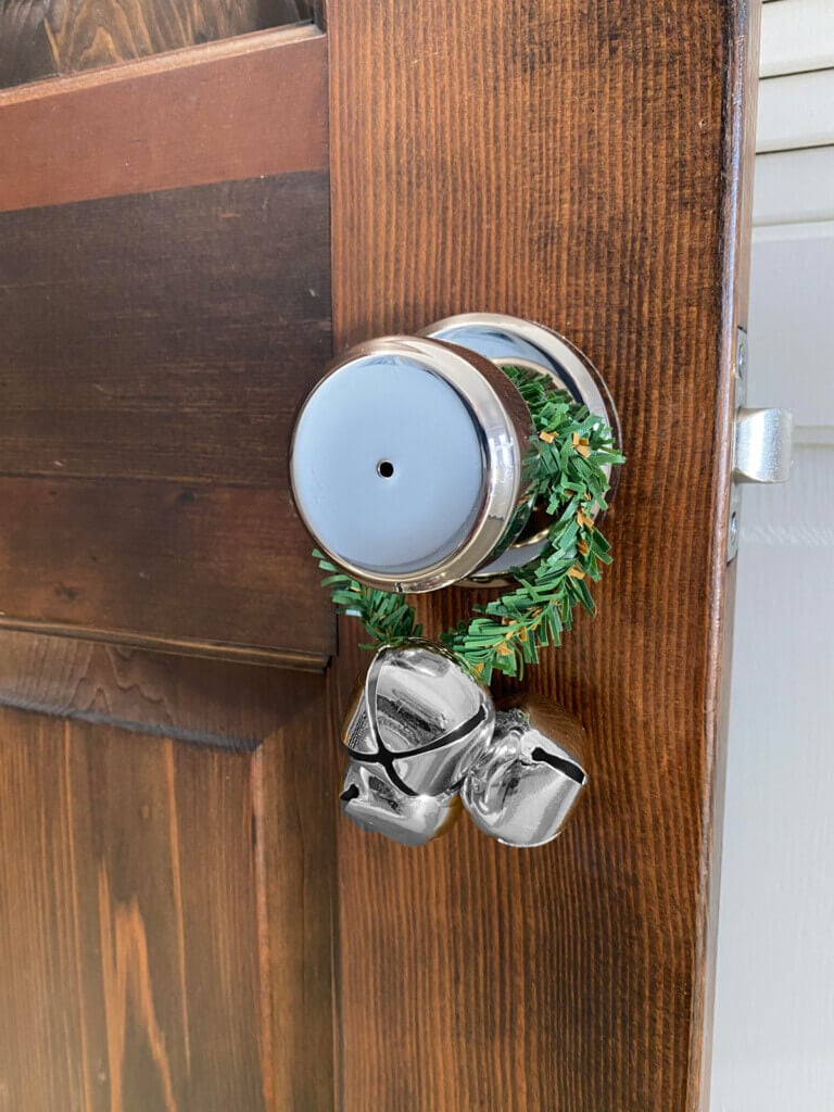 Christmas garland tie around a doorknob with a jingle bell attached.